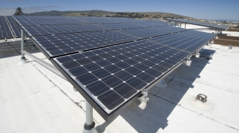 Solar installation on an apartment building roof including evacuated heat pipe tubing (EHPT) and electric solar panels.